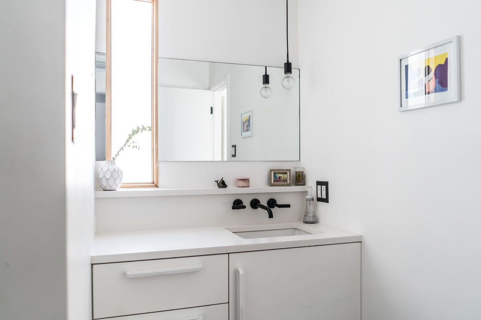 На фото: ванная комната среднего размера в стиле модернизм с плоскими фасадами, белыми фасадами, белыми стенами, врезной раковиной, душевой кабиной и столешницей из искусственного камня