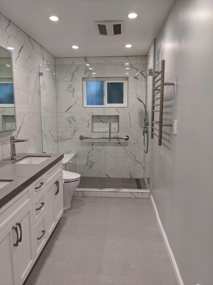 Example of a mid-sized transitional master white tile and porcelain tile porcelain tile, gray floor and double-sink bathroom design in San Francisco with recessed-panel cabinets, white cabinets, a one-piece toilet, white walls, an undermount sink, quartz countertops, a hinged shower door, gray countertops and a built-in vanity