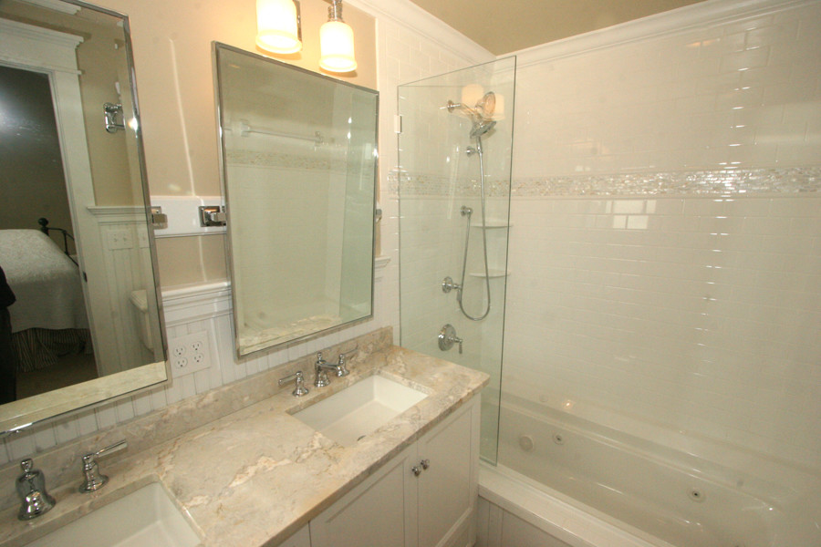 Exemple d'une salle de bain principale bord de mer de taille moyenne avec un lavabo encastré, un placard avec porte à panneau encastré, des portes de placard blanches, une baignoire posée, un combiné douche/baignoire, un carrelage blanc, un carrelage métro, un mur beige et un plan de toilette en granite.