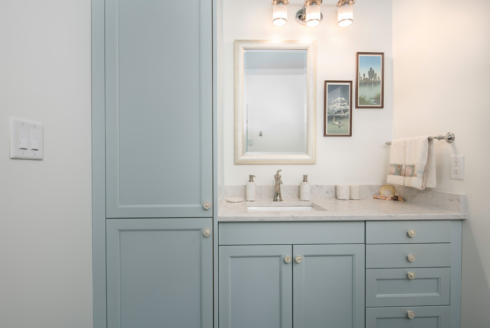 Cette image montre une petite salle de bain marine avec un placard à porte shaker, des portes de placard bleues, sol en béton ciré, un plan de toilette en quartz et un sol bleu.