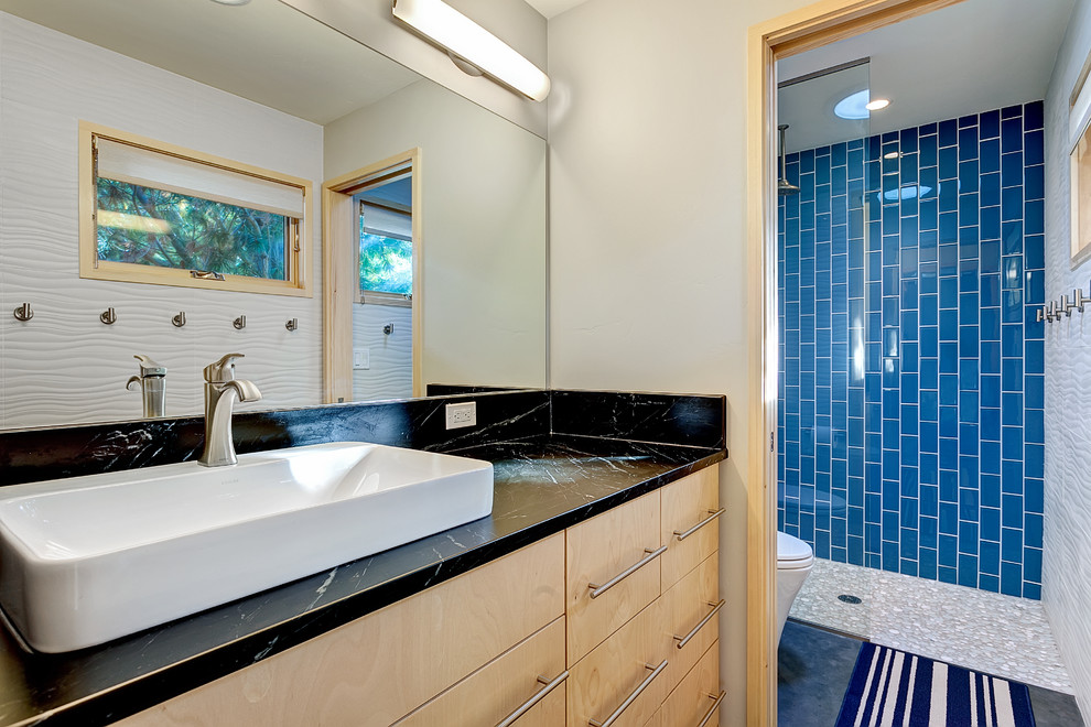 Immagine di una stanza da bagno design con lavabo a bacinella, ante in legno chiaro, top in saponaria, doccia a filo pavimento, piastrelle blu, piastrelle in ceramica, pareti bianche, pavimento in cemento e ante lisce
