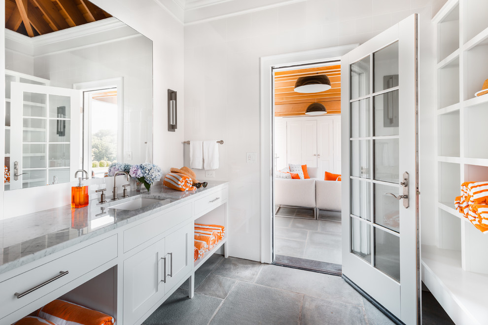 Diseño de cuarto de baño costero con armarios estilo shaker, puertas de armario blancas, paredes blancas, lavabo bajoencimera, suelo gris, encimeras grises y encimera de mármol