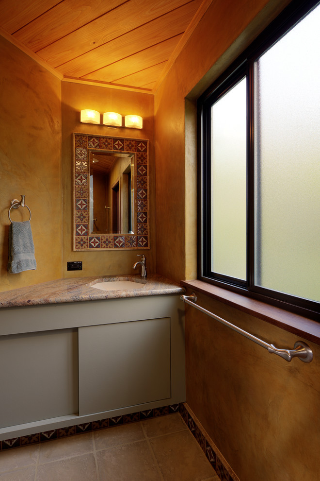 オースティンにある小さなトランジショナルスタイルのおしゃれな浴室 (緑のキャビネット、セメントタイルの床、アンダーカウンター洗面器、御影石の洗面台、ベージュの床) の写真