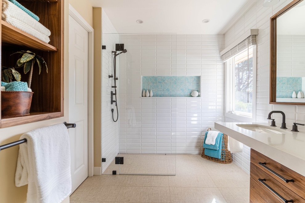 サンフランシスコにあるトランジショナルスタイルのおしゃれな浴室 (フラットパネル扉のキャビネット、中間色木目調キャビネット、バリアフリー、白いタイル、サブウェイタイル、ベージュの壁、アンダーカウンター洗面器、ベージュの床、オープンシャワー、白い洗面カウンター) の写真