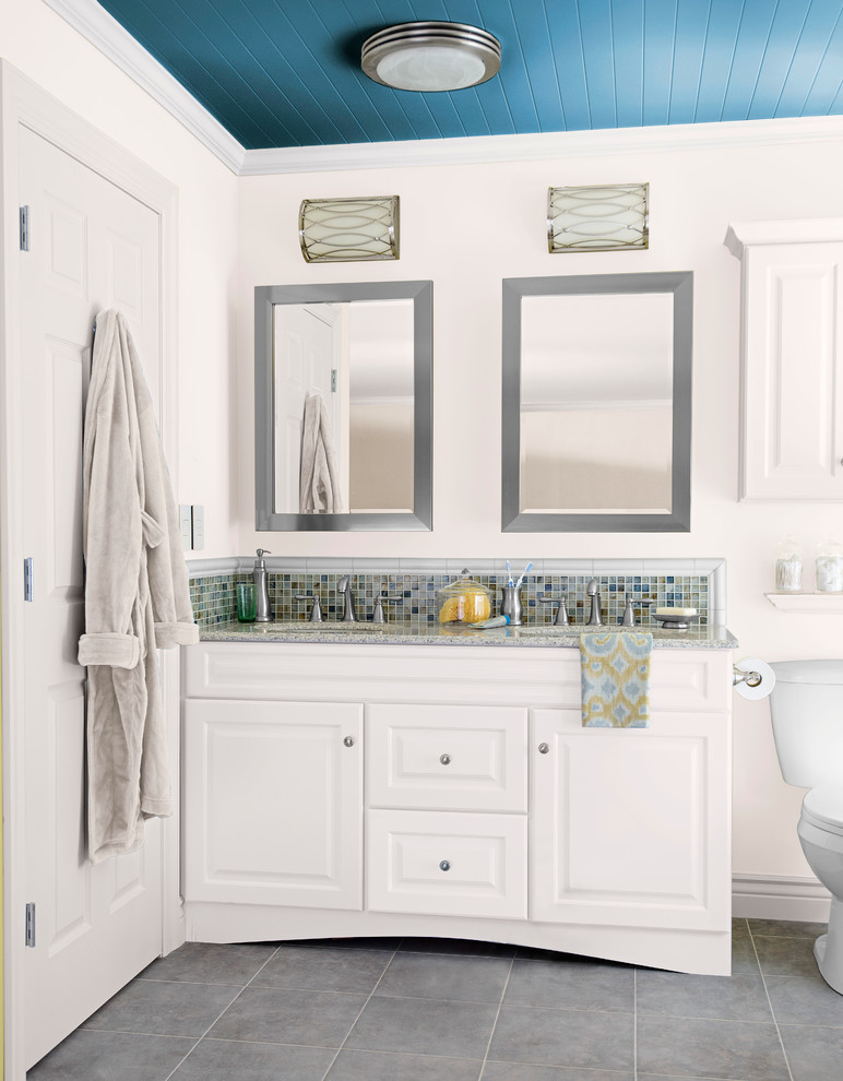 Inredning av ett klassiskt mellanstort en-suite badrum, med ett undermonterad handfat, luckor med upphöjd panel, vita skåp, granitbänkskiva, en toalettstol med separat cisternkåpa, flerfärgad kakel, mosaik, vita väggar och klinkergolv i keramik
