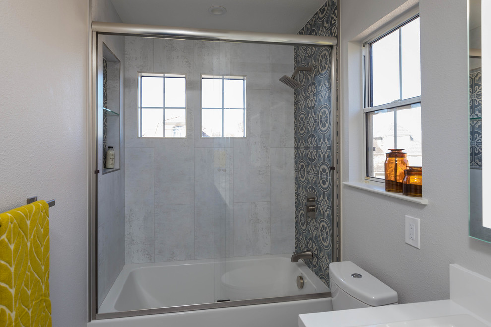 На фото: детская ванная комната среднего размера в стиле модернизм с фасадами в стиле шейкер, серыми фасадами, полновстраиваемой ванной, душем над ванной, унитазом-моноблоком, серой плиткой, керамической плиткой, серыми стенами, полом из керамогранита, врезной раковиной, столешницей из гранита, серым полом, душем с раздвижными дверями и белой столешницей