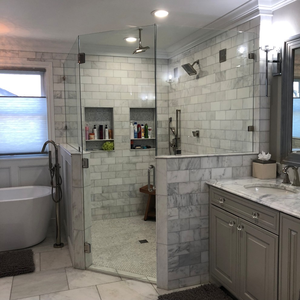 Пример оригинального дизайна: большая главная ванная комната в классическом стиле с фасадами с выступающей филенкой, серыми фасадами, отдельно стоящей ванной, душевой комнатой, унитазом-моноблоком, серой плиткой, мраморной плиткой, серыми стенами, мраморным полом, накладной раковиной, мраморной столешницей, серым полом и душем с распашными дверями