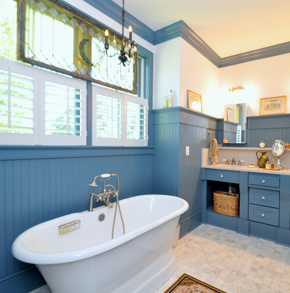Foto di una stanza da bagno padronale tradizionale di medie dimensioni con consolle stile comò, ante blu, vasca freestanding, WC a due pezzi, piastrelle grigie, piastrelle a mosaico, pareti blu, pavimento in marmo, lavabo integrato e top in marmo