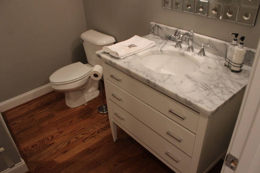 This is an example of a medium sized modern bathroom in Other with a submerged sink, freestanding cabinets, white cabinets, marble worktops, an alcove shower, a one-piece toilet, grey walls and medium hardwood flooring.