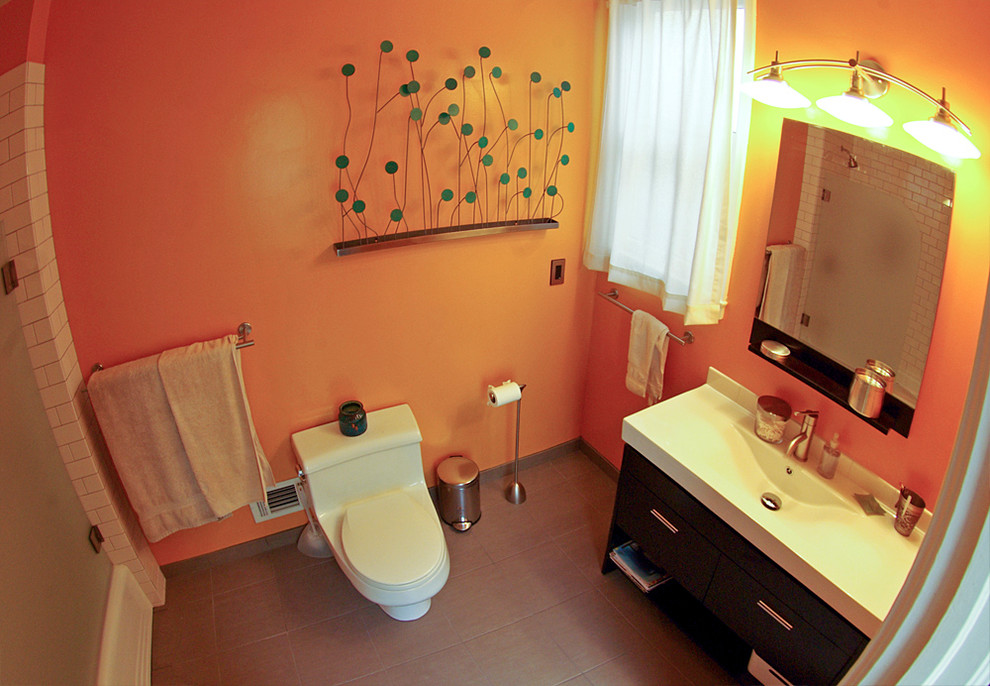 Idée de décoration pour une salle de bain principale design en bois foncé de taille moyenne avec un lavabo intégré, un placard en trompe-l'oeil, un plan de toilette en surface solide, un combiné douche/baignoire, WC à poser, un carrelage marron, des carreaux de porcelaine, un mur orange et un sol en carrelage de porcelaine.