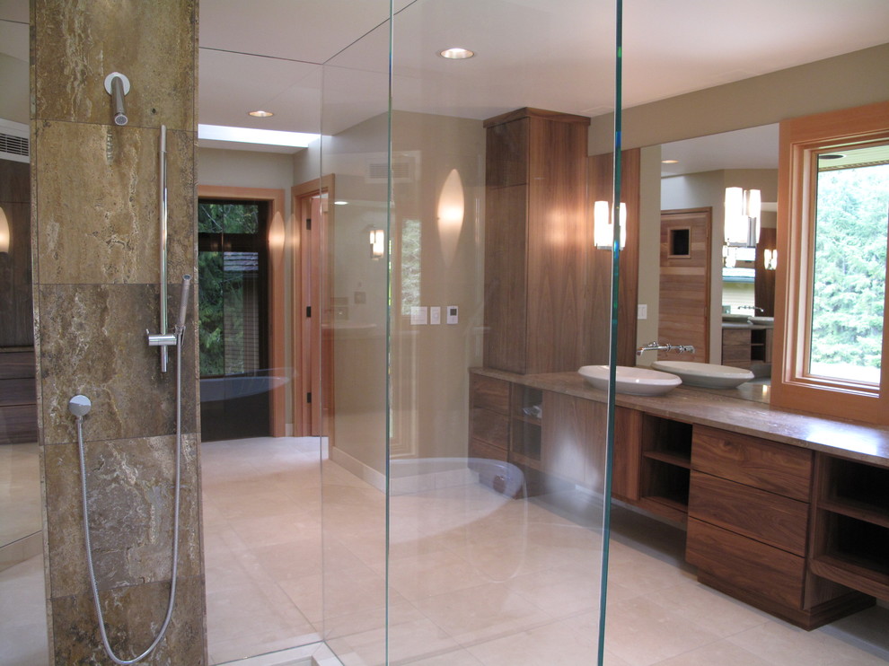 Design ideas for a contemporary bathroom in Seattle with a vessel sink, flat-panel cabinets, dark wood cabinets, a freestanding bath, a walk-in shower, a one-piece toilet, beige tiles, stone tiles, beige walls and limestone flooring.