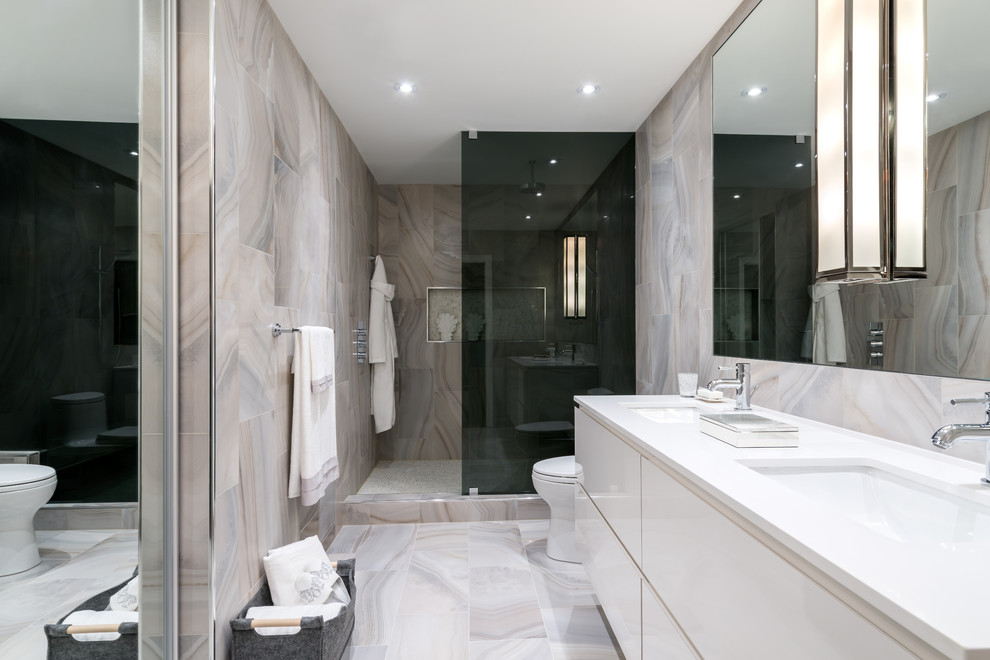 Klassisk inredning av ett stort en-suite badrum, med ett undermonterad handfat, släta luckor, vita skåp, bänkskiva i kvarts, en öppen dusch, porslinskakel, klinkergolv i porslin, beige kakel och grå kakel