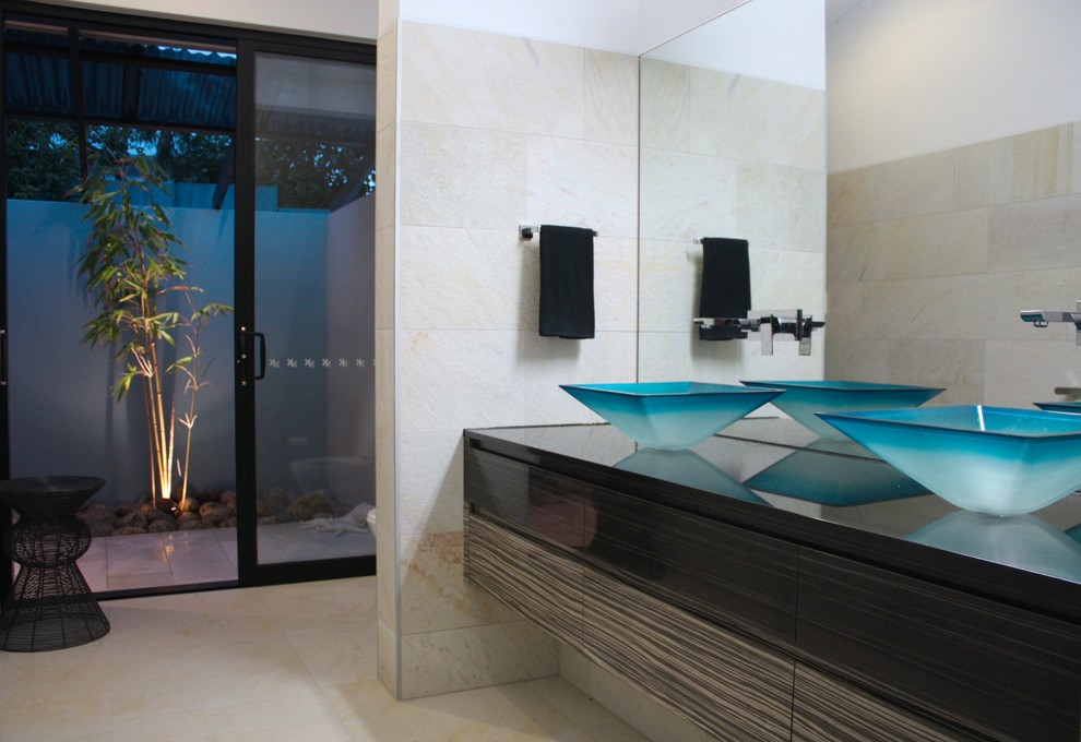 Imagen de cuarto de baño principal costero con lavabo sobreencimera, armarios con paneles empotrados, puertas de armario de madera en tonos medios, encimera de granito y baldosas y/o azulejos beige