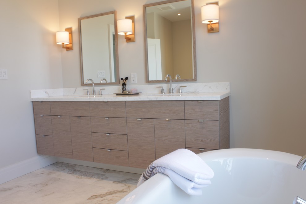 Inredning av ett modernt stort en-suite badrum, med släta luckor, skåp i ljust trä, ett fristående badkar, en dusch i en alkov, beige väggar, marmorgolv, ett integrerad handfat och marmorbänkskiva
