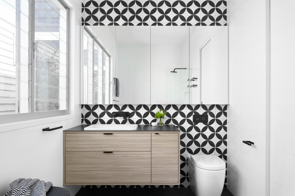 Photo of a medium sized contemporary ensuite bathroom in Melbourne with beaded cabinets, light wood cabinets, a freestanding bath, a walk-in shower, multi-coloured tiles, mosaic tiles, a built-in sink, solid surface worktops and black worktops.