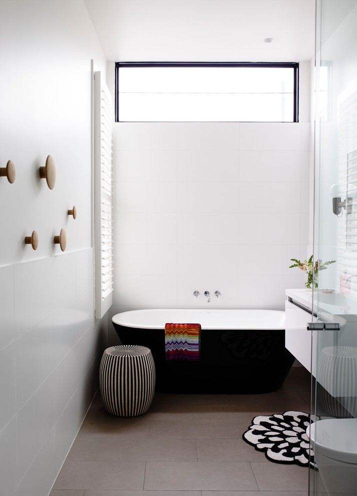 Foto på ett funkis badrum, med släta luckor, vita skåp, ett fristående badkar, vit kakel och vita väggar