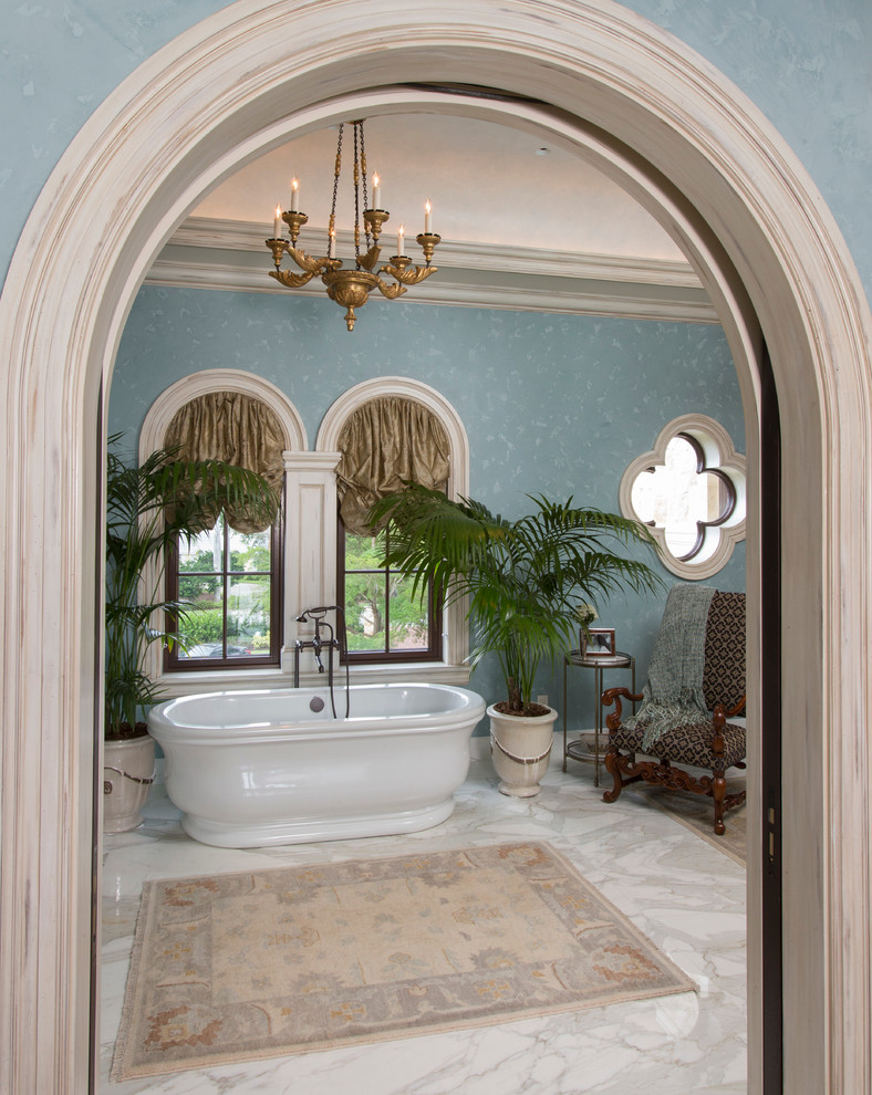 На фото: большая главная ванная комната в средиземноморском стиле с отдельно стоящей ванной, синими стенами, мраморным полом и белым полом с