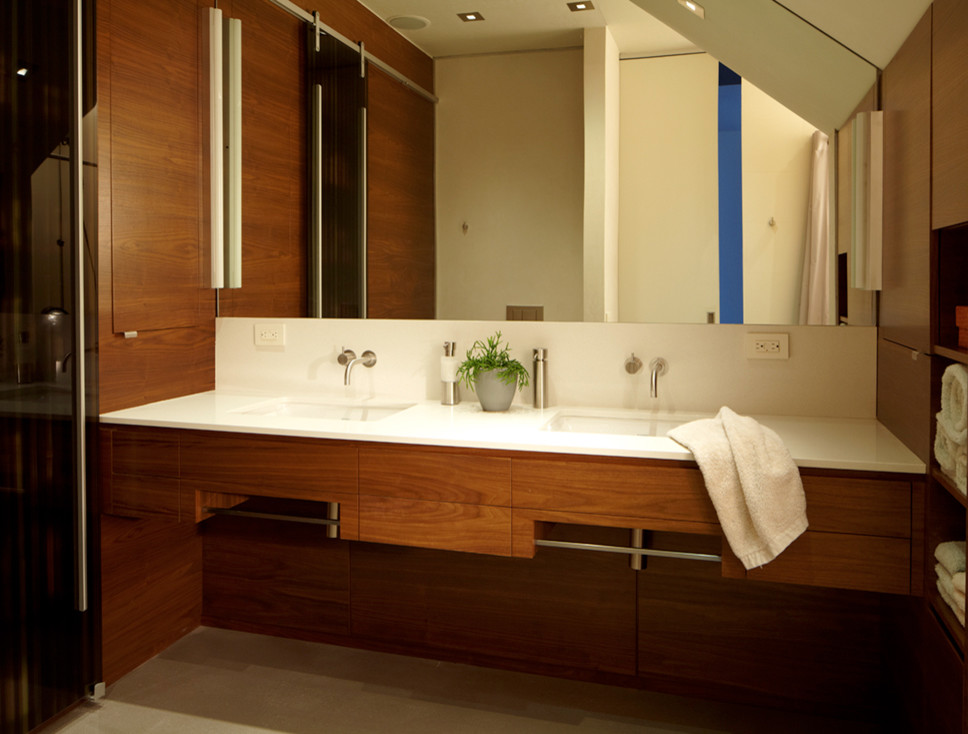 Bild på ett stort funkis badrum, med släta luckor, skåp i mellenmörkt trä, vita väggar, betonggolv, ett undermonterad handfat och bänkskiva i akrylsten