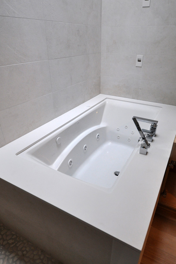Idéer för ett litet modernt en-suite badrum, med släta luckor, ett undermonterat badkar, en hörndusch, beige kakel, porslinskakel, beige väggar, bänkskiva i kvartsit, mellanmörkt trägolv och brunt golv