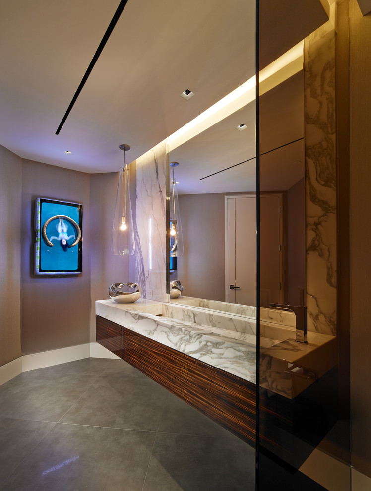 Modelo de cuarto de baño actual de tamaño medio con puertas de armario de madera oscura, baldosas y/o azulejos grises, paredes beige, aseo y ducha, encimera de mármol y armarios con paneles lisos