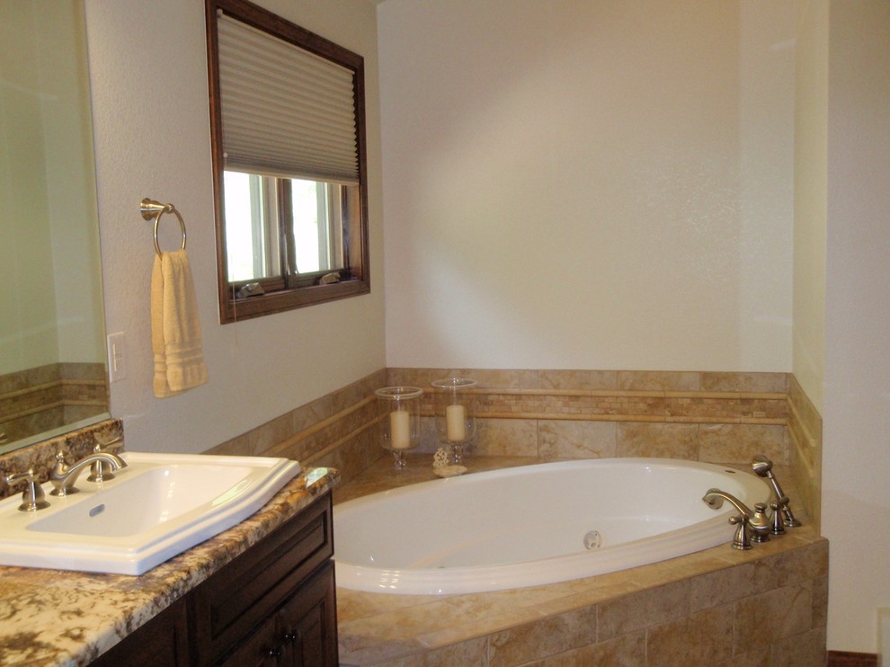 Aménagement d'une salle de bain principale classique en bois foncé de taille moyenne avec un placard à porte affleurante, une baignoire d'angle, un mur blanc, un lavabo posé et un plan de toilette en granite.