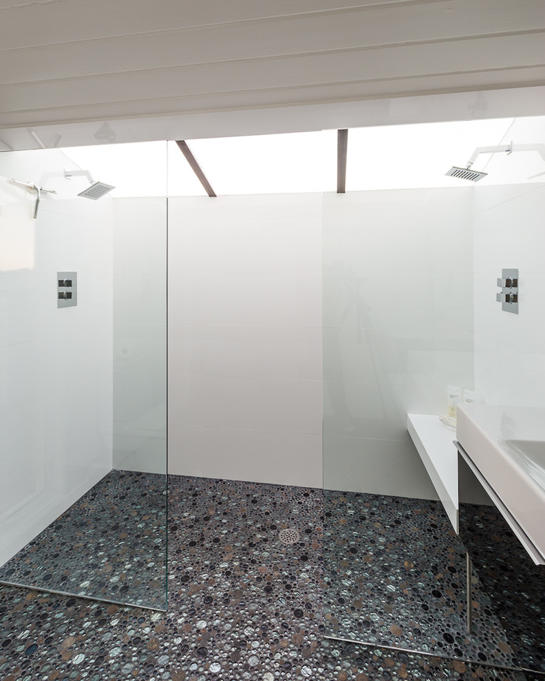 Modelo de cuarto de baño principal minimalista de tamaño medio con baldosas y/o azulejos blancos, paredes blancas, armarios con paneles lisos, puertas de armario negras, lavabo integrado, ducha a ras de suelo y suelo de baldosas tipo guijarro
