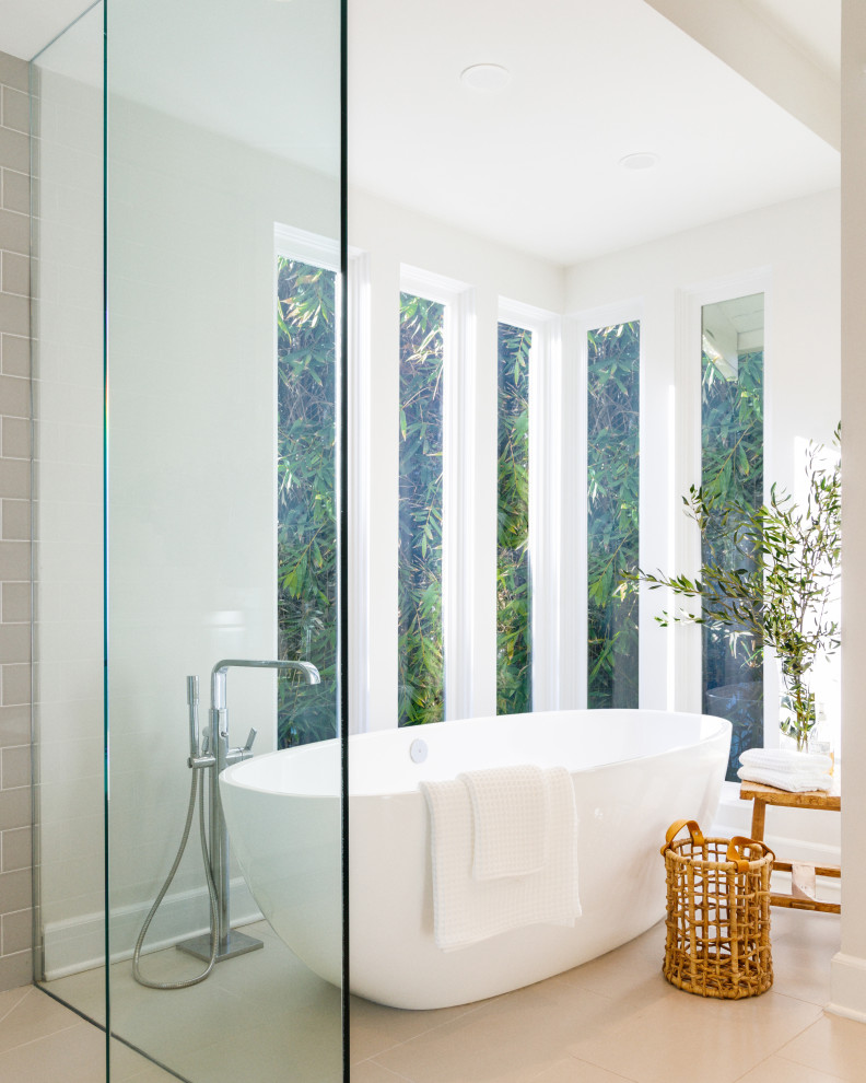 Cette image montre une salle de bain design avec une baignoire indépendante, un mur blanc et un sol beige.