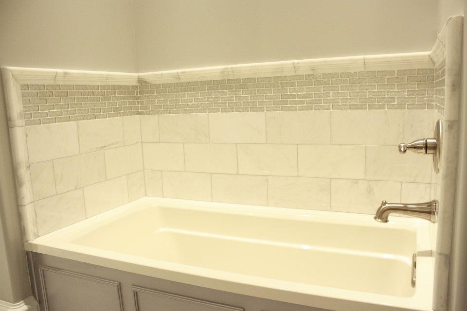Inredning av ett modernt mellanstort badrum med dusch, med grå skåp, granitbänkskiva, grå kakel, stenkakel, marmorgolv, ett badkar i en alkov och grå väggar