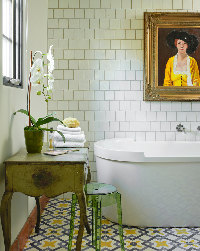 Cette image montre une salle de bain méditerranéenne avec une baignoire indépendante, un carrelage blanc, un mur blanc et un sol multicolore.