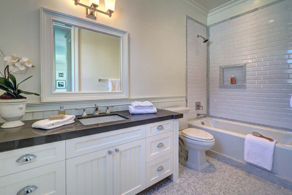 Bathroom - mid-sized white tile and stone slab marble floor bathroom idea in Los Angeles with an undermount sink, recessed-panel cabinets, white cabinets, quartz countertops, a one-piece toilet and white walls