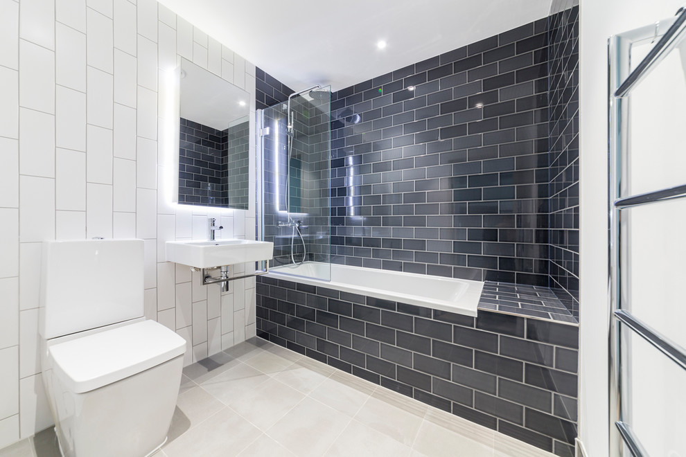 Ispirazione per una stanza da bagno design di medie dimensioni con vasca/doccia, WC monopezzo, pareti bianche, lavabo sospeso, pavimento grigio e porta doccia a battente