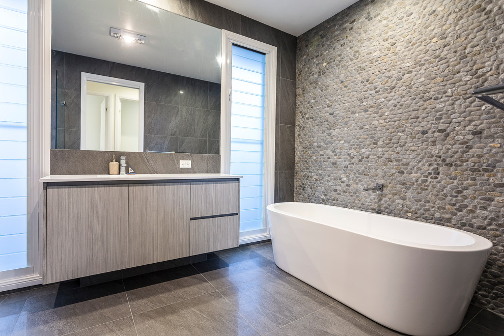 Modernes Badezimmer mit Unterbauwaschbecken, flächenbündigen Schrankfronten, freistehender Badewanne, grauen Fliesen, Steinfliesen, grauer Wandfarbe, Schieferboden und grauen Schränken in Sunshine Coast