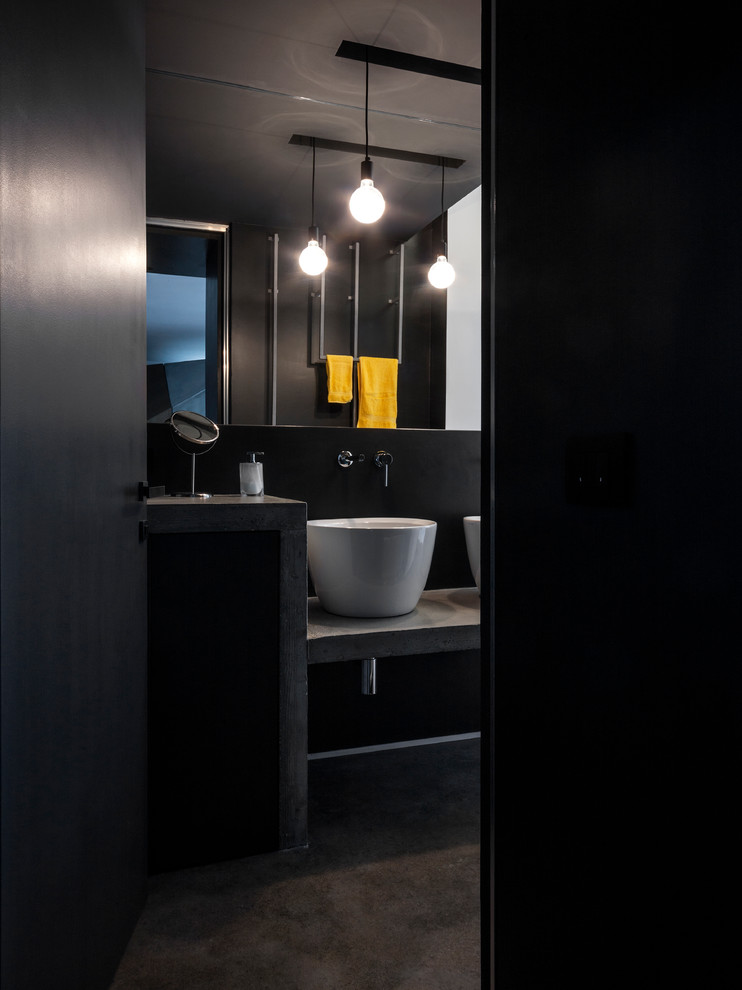 На фото: ванная комната в стиле лофт с черными стенами, бетонным полом, настольной раковиной, столешницей из бетона, черным полом и серой столешницей