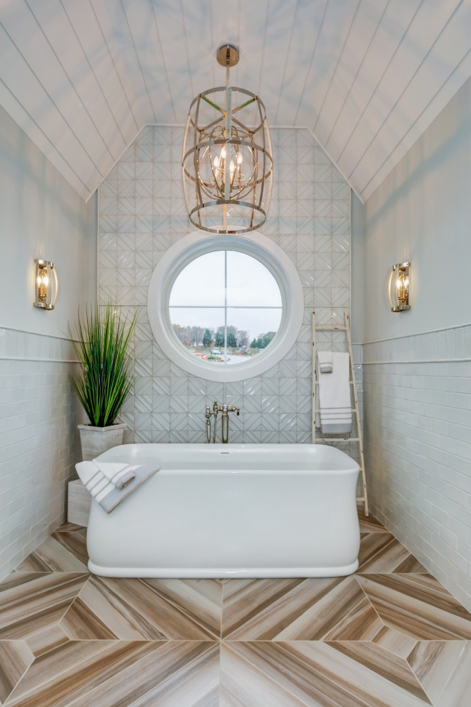 Foto på ett stort maritimt en-suite badrum, med ett fristående badkar, grå kakel, glaskakel, klinkergolv i porslin och beiget golv