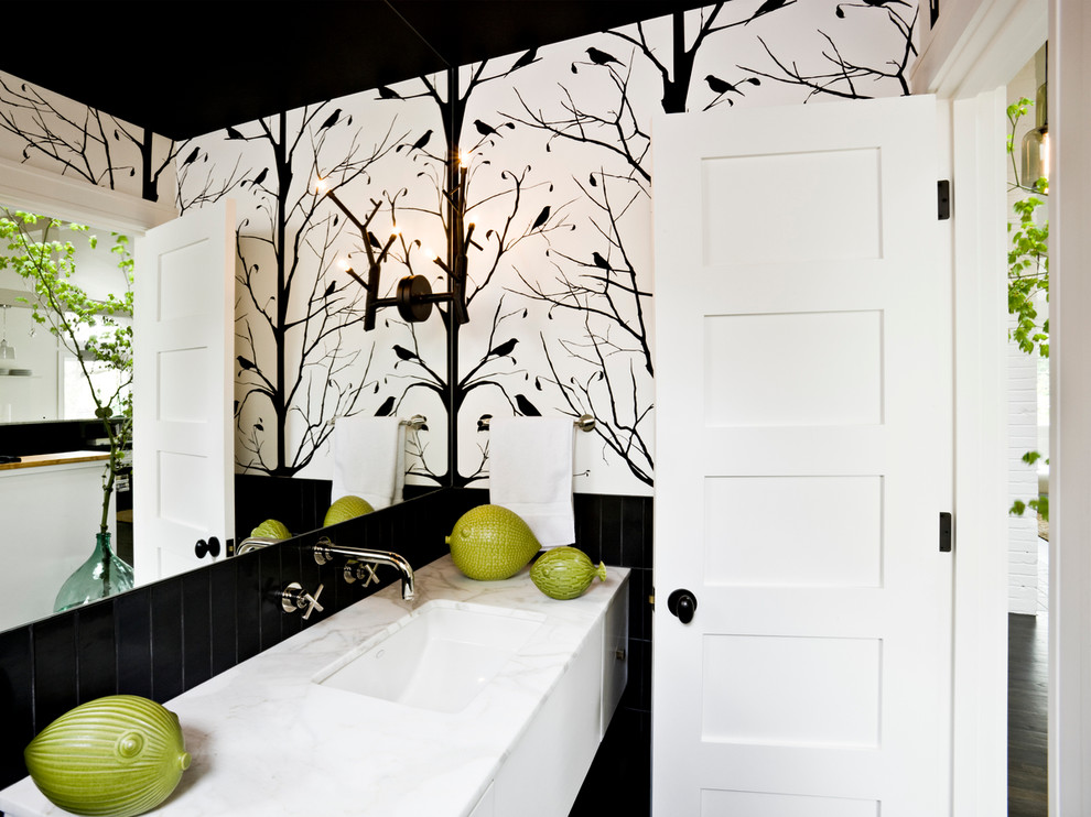 Modern inredning av ett badrum, med marmorbänkskiva och svarta väggar