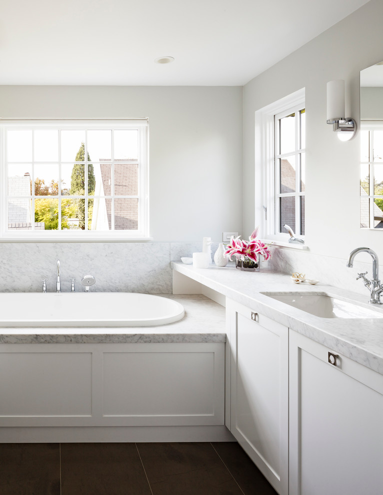 Foto på ett mellanstort funkis badrum, med ett undermonterad handfat, skåp i shakerstil, vita skåp, marmorbänkskiva, ett platsbyggt badkar, en toalettstol med separat cisternkåpa, vit kakel, keramikplattor och grå väggar