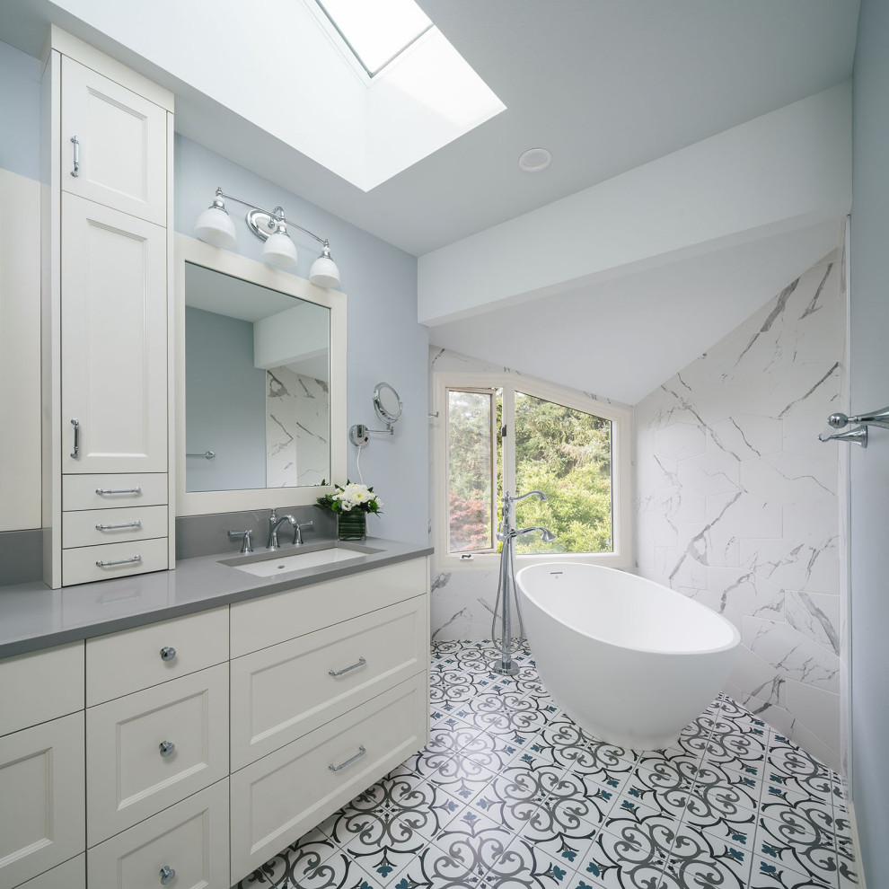 Photo of a traditional bathroom in Portland with recessed-panel cabinets, white cabinets, a freestanding bath, grey walls, a submerged sink, multi-coloured floors and grey worktops.