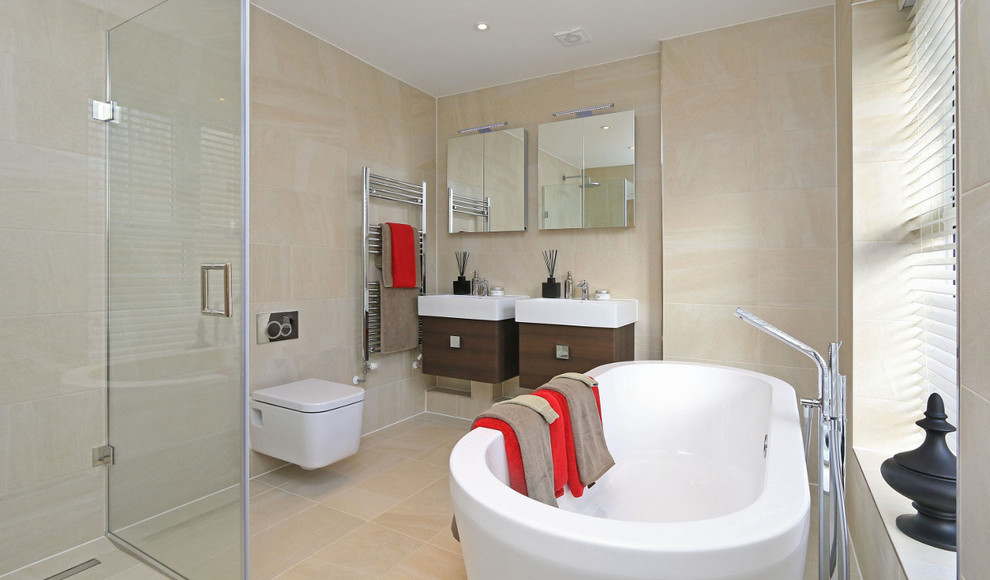 Inspiration för moderna en-suite badrum, med ett konsol handfat, skåp i mörkt trä, ett fristående badkar, en vägghängd toalettstol och beige kakel