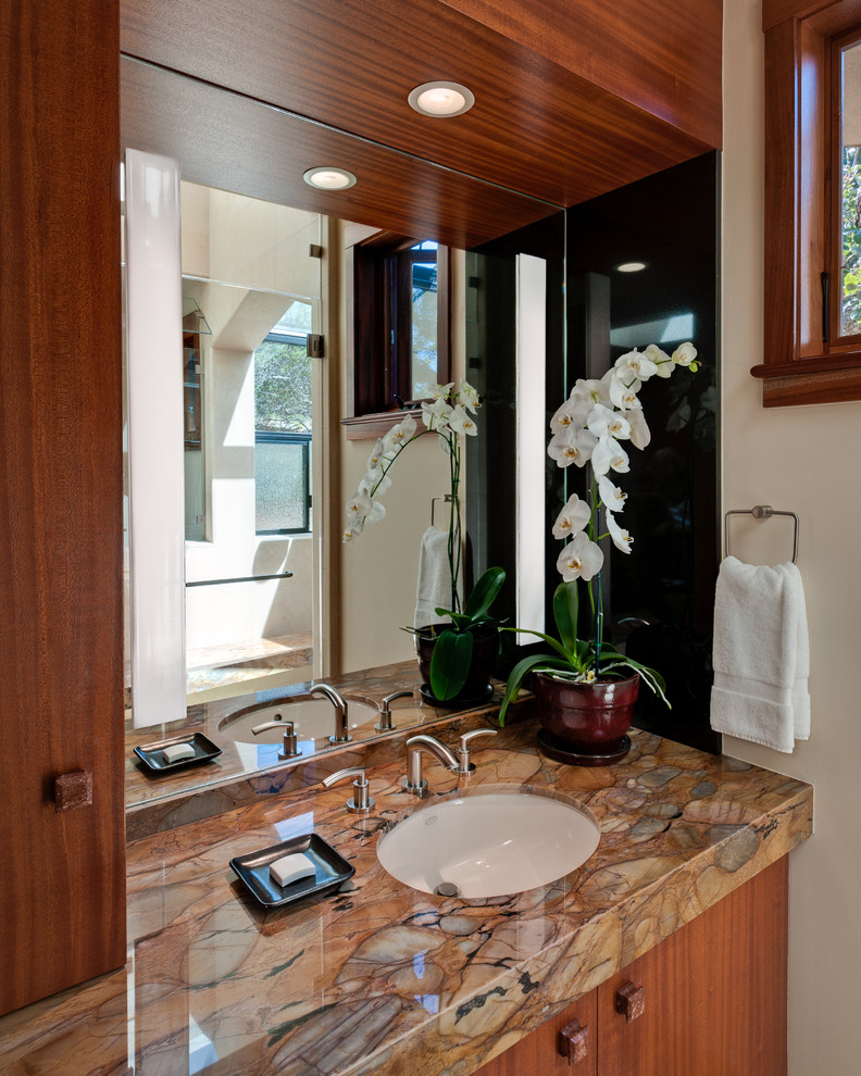 Modelo de cuarto de baño actual de tamaño medio con armarios con paneles lisos, puertas de armario de madera oscura, ducha empotrada, paredes blancas, aseo y ducha, lavabo bajoencimera y encimera de acrílico