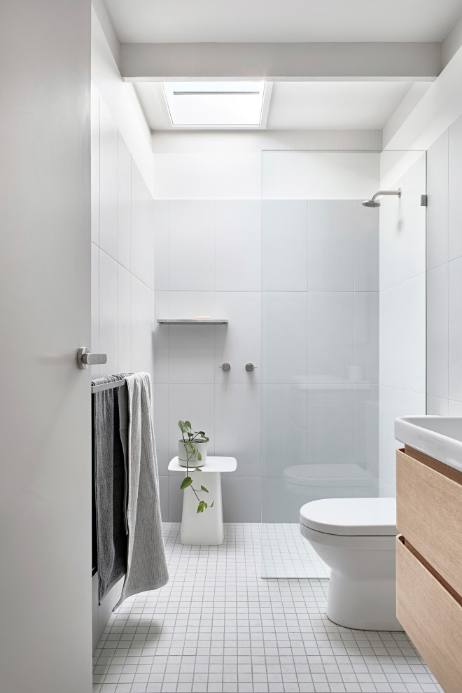 Modernes Badezimmer mit flächenbündigen Schrankfronten, hellen Holzschränken, Duschnische, grauen Fliesen, weißer Wandfarbe, Mosaik-Bodenfliesen, Waschtischkonsole, grauem Boden, offener Dusche, Einzelwaschbecken und schwebendem Waschtisch in Melbourne