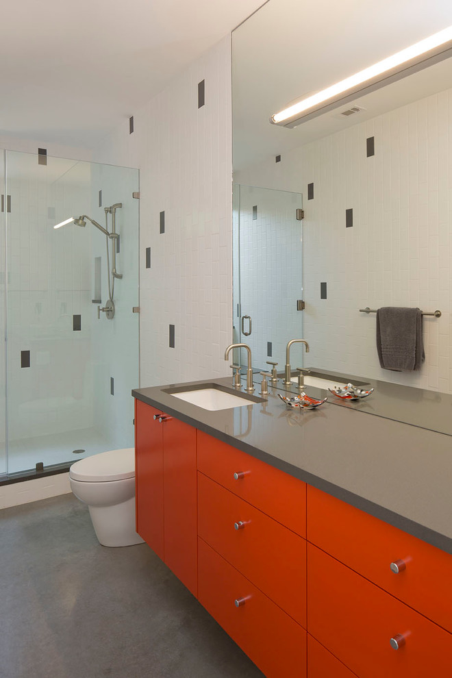 オースティンにあるコンテンポラリースタイルのおしゃれなバスルーム (浴槽なし) (アンダーカウンター洗面器、フラットパネル扉のキャビネット、赤いキャビネット、クオーツストーンの洗面台、アルコーブ型シャワー、一体型トイレ	、セラミックタイル、コンクリートの床、グレーのタイル、白いタイル、白い壁、グレーの洗面カウンター) の写真