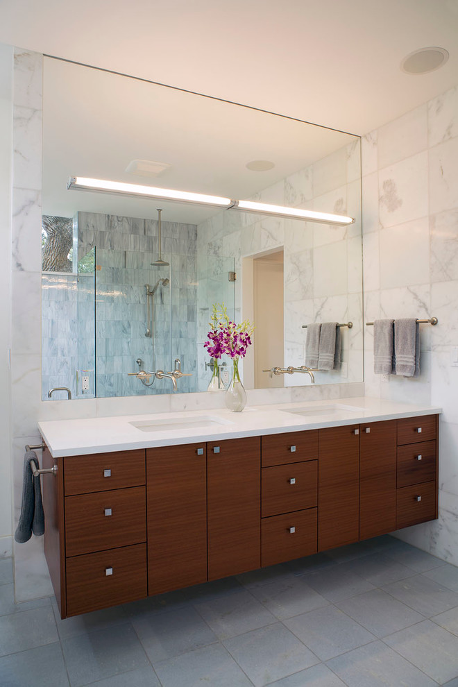 Example of a large trendy master white tile and stone tile porcelain tile alcove shower design in Austin with an undermount sink, flat-panel cabinets, dark wood cabinets, quartz countertops and white walls