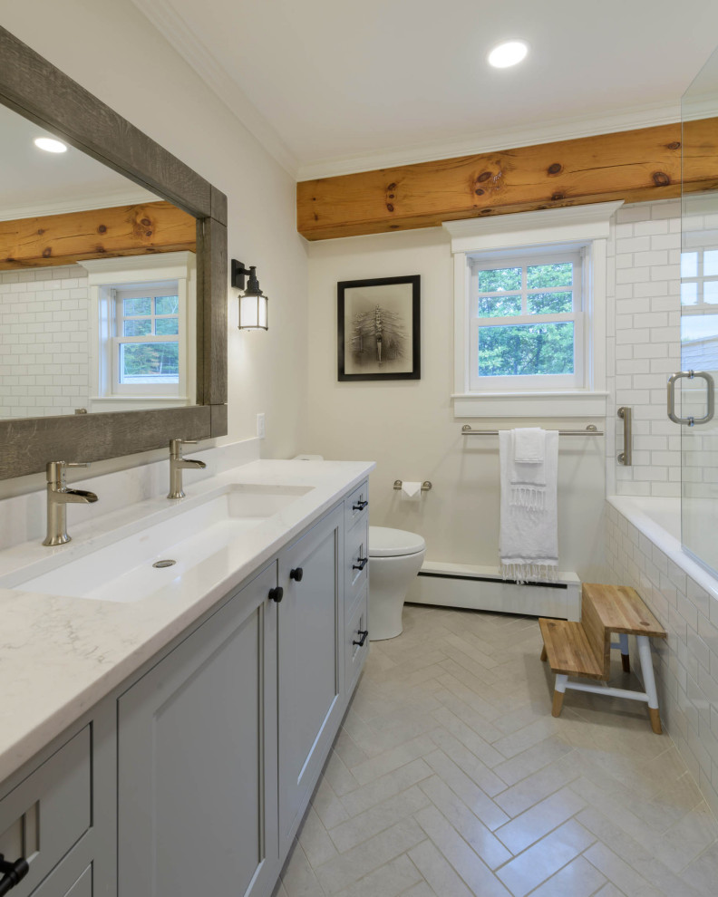 Diseño de cuarto de baño único y a medida clásico renovado grande con suelo de baldosas de porcelana, encimera de cuarzo compacto, suelo gris, encimeras blancas, armarios con paneles empotrados, puertas de armario grises, bañera empotrada, combinación de ducha y bañera, sanitario de dos piezas, baldosas y/o azulejos blancos, baldosas y/o azulejos de cemento, paredes beige, aseo y ducha, lavabo de seno grande y ducha con puerta con bisagras