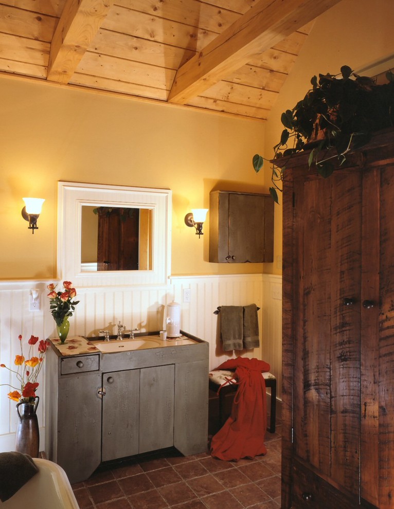 Idee per una stanza da bagno padronale tradizionale con ante lisce, ante blu, piastrelle marroni, pareti gialle e lavabo sottopiano
