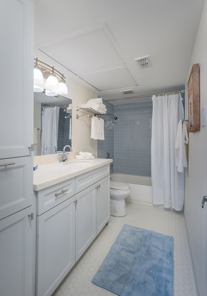 На фото: главная ванная комната среднего размера в стиле модернизм с фасадами с выступающей филенкой, серыми фасадами, накладной ванной, душем над ванной, раздельным унитазом, синей плиткой, керамической плиткой, белыми стенами, полом из цементной плитки, врезной раковиной, столешницей из искусственного кварца, белым полом и шторкой для ванной с