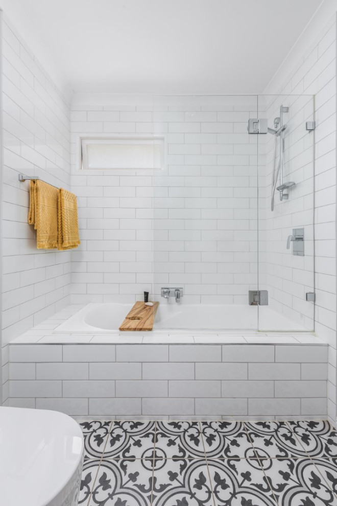 Foto på ett litet retro vit en-suite badrum, med skåp i shakerstil, beige skåp, ett platsbyggt badkar, en dusch/badkar-kombination, en toalettstol med hel cisternkåpa, vit kakel, tunnelbanekakel, vita väggar, cementgolv, ett undermonterad handfat, bänkskiva i kvarts, vitt golv och dusch med gångjärnsdörr