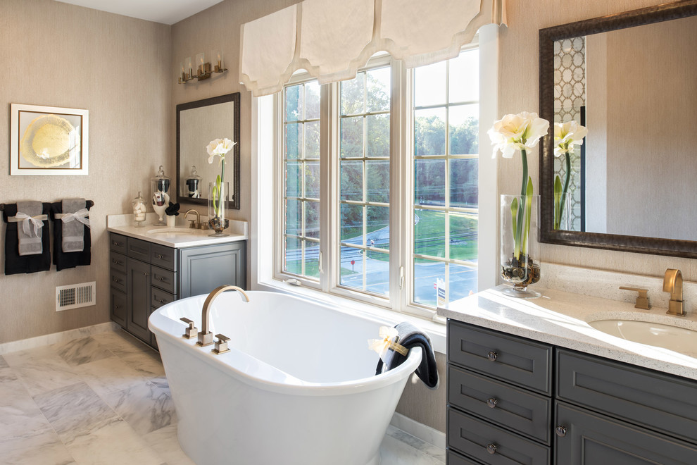 Immagine di una stanza da bagno padronale chic con ante grigie, vasca freestanding, pareti beige, pavimento in marmo e lavabo sottopiano