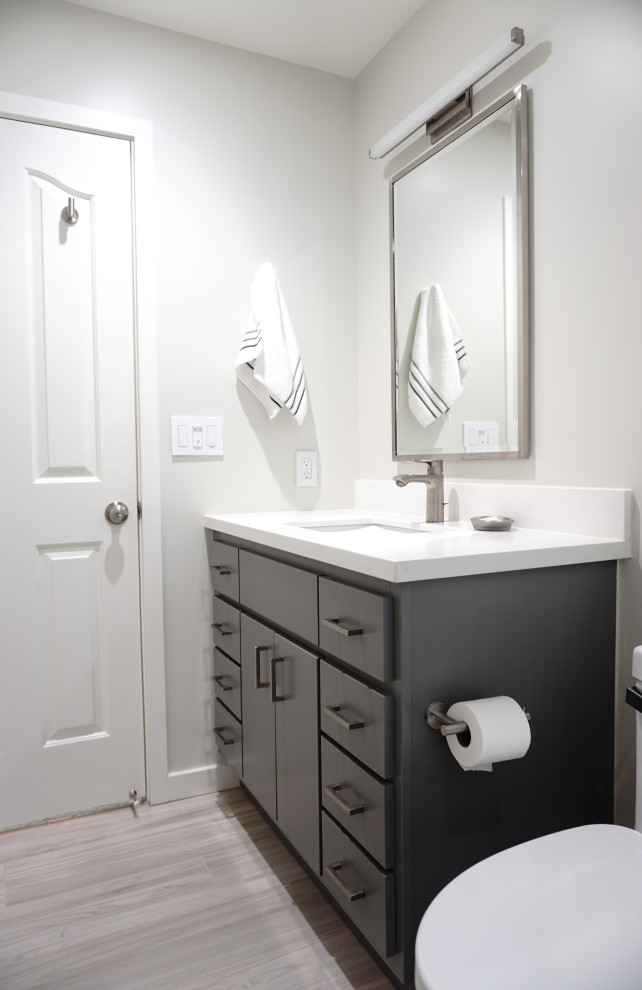 This is an example of a medium sized contemporary bathroom in San Francisco with flat-panel cabinets, grey cabinets, an alcove bath, a shower/bath combination, a one-piece toilet, white tiles, metro tiles, white walls, wood-effect flooring, a submerged sink, engineered stone worktops, beige floors, a sliding door, white worktops, a wall niche, a single sink and a built in vanity unit.