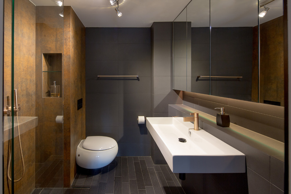Mid-sized minimalist master gray tile and porcelain tile ceramic tile bathroom photo in Sydney with glass-front cabinets, a wall-mount toilet, gray walls, a wall-mount sink and gray countertops