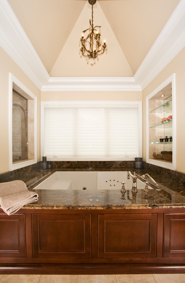 Cette image montre une très grande salle de bain principale traditionnelle en bois brun avec un plan de toilette en marbre, une baignoire encastrée, une douche double, un carrelage marron, un lavabo encastré, WC séparés et un mur gris.